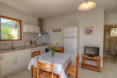a kitchen with a table and a refrigerator and a tv at L'AMANDIER -LE FIGUIER-LES LAURIERS ROSES in Ajaccio