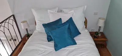 a bed with white pillows and blue pillows at Super villa idyllique & antique avec vue mer imprenable in Olmeto