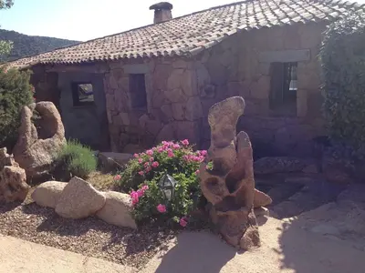 a small stone house with flowers in front of it at Gianni Location Palombaggia in Porto-Vecchio