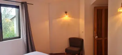 a bedroom with a chair and a window at Gianni Location Palombaggia in Porto-Vecchio