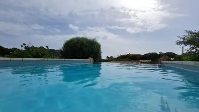 a large swimming pool with blue water at Gianni Location Palombaggia in Porto-Vecchio
