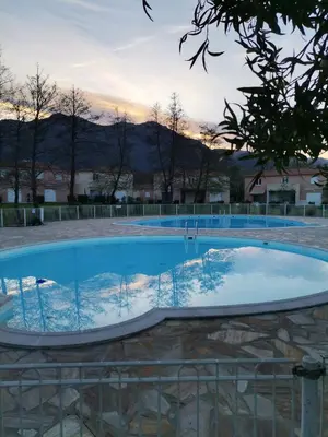 a large swimming pool with a sunset in the background at Esperanza in Moriani Plage