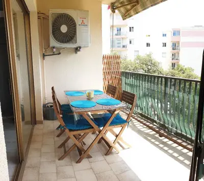 a table and chairs on a balcony with a fan at Beau T3 70m2 Ajaccio in Ajaccio