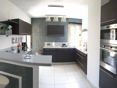 a kitchen with black cabinets and a white floor at Beau T3 70m2 Ajaccio in Ajaccio