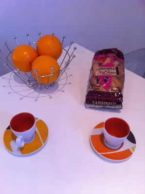 a table with two cups of coffee and a basket of oranges at Bel F2 près de la plage in Ajaccio