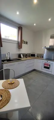 a kitchen with white cabinets and a table in it at Bel F2 près de la plage in Ajaccio