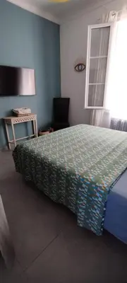 a bedroom with a bed and a table and a window at Bel F2 près de la plage in Ajaccio