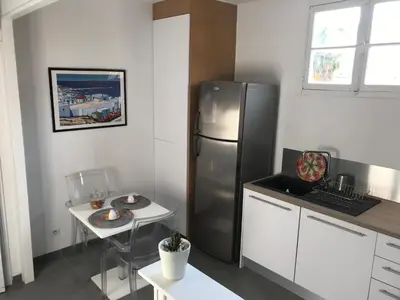 a kitchen with a stainless steel refrigerator and a table at Bel F2 près de la plage in Ajaccio