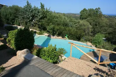 a swimming pool in a yard with a wooden staircase at Sunrise T2 avec jacuzzi vue mer in Porto-Vecchio
