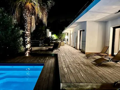 a deck with chairs and a swimming pool at night at le Pied à Terre 2 PORTICCIO in Porticcio