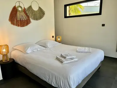 a bedroom with a white bed with towels and a window at le Pied à Terre 2 PORTICCIO in Porticcio