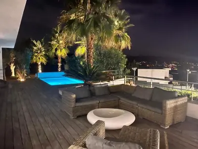 a rooftop patio with couches and a pool at night at le Pied à Terre 2 PORTICCIO in Porticcio