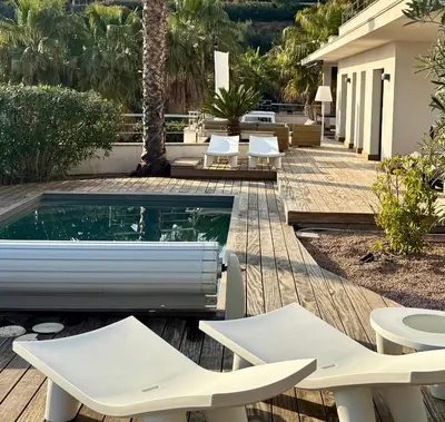 a swimming pool with two white chairs and a table at le Pied à Terre 2 PORTICCIO in Porticcio