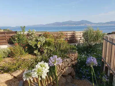 a garden with flowers in front of a fence at Villa ARIA et MAQUIS, Villa 4 chambres- Piscine - Plage à pied - vue mer in Pietrosella
