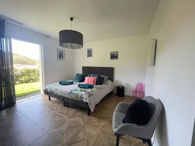 a bedroom with a bed and a chair and a window at Magnifique villa récente entre mer et montagne située entre Ajaccio et Porticcio in Cauro