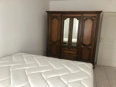 a bedroom with a bed and a wooden cabinet at Superbe Appartement Vue Montagne Proximités Grandes Surfaces in Poggi