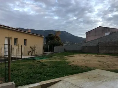 an empty yard with a building and a mountain at Superbe Appartement Vue Montagne Proximités Grandes Surfaces in Poggi