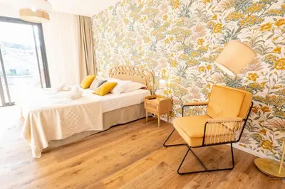 a bedroom with a bed and a chair and floral wallpaper at Villa Renajolo 16 pers piscine chauffée 2 min plage en voiture in Sainte-Lucie de Porto-Vecchio