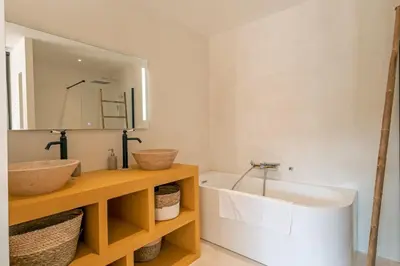 a bathroom with a sink and a mirror and a tub at Villa Renajolo 16 pers piscine chauffée 2 min plage en voiture in Sainte-Lucie de Porto-Vecchio