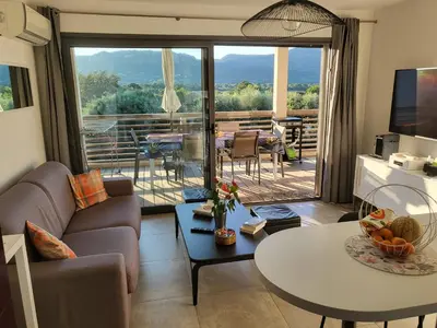 a living room with a couch and a table at Appartement de standing avec piscine et terrasse in Porto-Vecchio