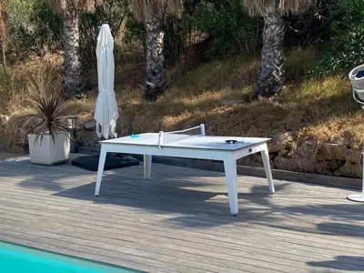 a white ping pong table and an umbrella next to a pool at Appartement - Maison 