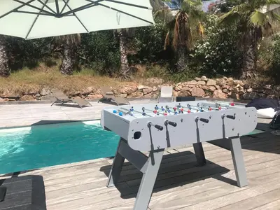 a foosball table with an umbrella next to a pool at Appartement - Maison 