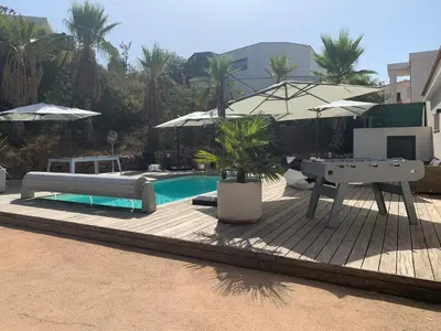 a pool with a bench and an umbrella and a table at Appartement - Maison 