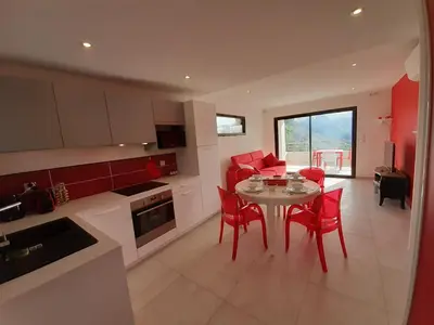 a kitchen and dining room with a table and red chairs at Domaine de Pacciolello - Porticcio in Porticcio