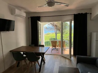 a living room with a table and chairs and a sliding glass door at Résidence Punta paliagi in Calcatoggio