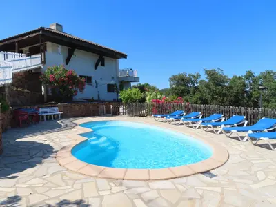a swimming pool with chairs and a house at Maison Le Guetali in Sainte-Lucie de Porto-Vecchio