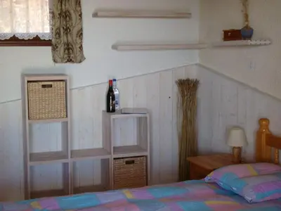 a bedroom with a bed and a bottle of wine at Maison Le Guetali in Sainte-Lucie de Porto-Vecchio