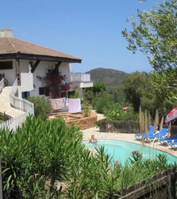 a person laying in a swimming pool next to a house at Maison Le Guetali in Sainte-Lucie de Porto-Vecchio