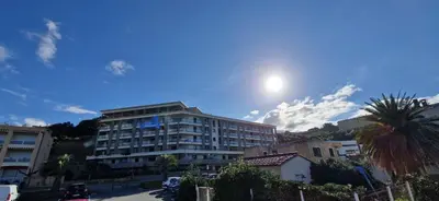 a view of a building with the sun in the sky at T2 Fronte Di Mare de standing en bord de mer et du centre du village de Propriano in Propriano