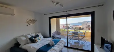 a living room with a couch and a balcony with a view at T2 Fronte Di Mare de standing en bord de mer et du centre du village de Propriano in Propriano
