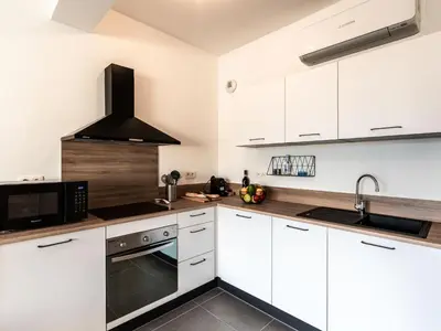 a kitchen with white cabinets and a black microwave at Studio Studio Côté Sud 29 by Interhome in Porto-Vecchio