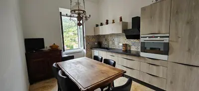 a kitchen with a wooden table and some chairs at Bel & ancien appartement T3 rénové dans Sartène in Sartène