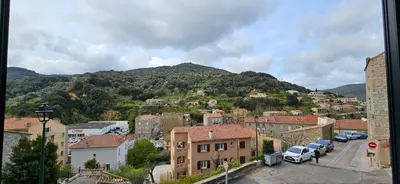 a town with cars parked in front of a mountain at Bel & ancien appartement T3 rénové dans Sartène in Sartène