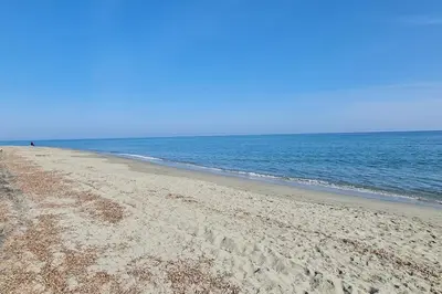 a sandy beach with the ocean in the background at Magnifique villa avec piscine en bord de Mer in Lucciana