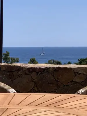 a wooden deck with a sail boat in the water at Villa Falcone marinu ***** in Kamiesch