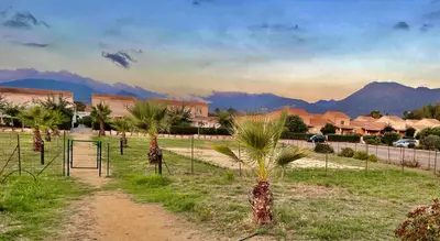 a dirt path with palm trees and mountains in the background at Casa in Cervione