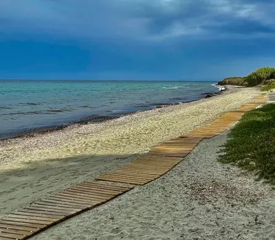 a wooden pathway on a beach next to the ocean at Casa in Cervione