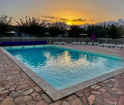 a swimming pool with chairs and a sunset in the background at Casa in Cervione