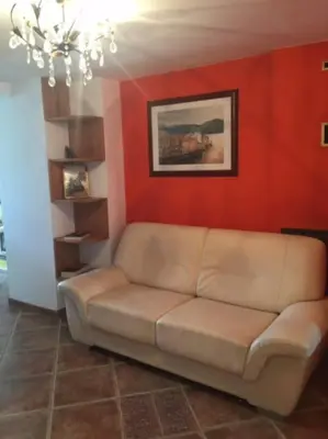 a couch in a living room with a red wall at Appartement dans maison de village in Piana