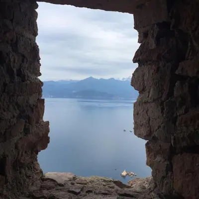 a view of the water through a stone window at Appartement dans maison de village in Piana