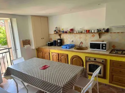a kitchen with a table and a kitchen with a table and chairs at Appartement dans maison de village in Piana