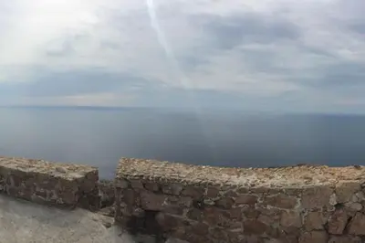 a brick wall with the ocean in the background at Appartement dans maison de village in Piana
