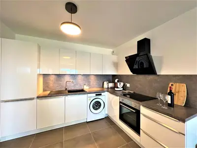 a kitchen with white cabinets and a washer and dryer at BEL' ORIZONTE proche centre ville et plage in Propriano