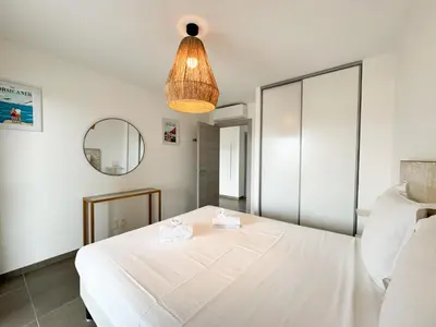 a bedroom with a white bed and a mirror at BEL' ORIZONTE proche centre ville et plage in Propriano