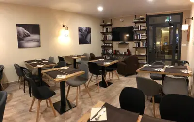 a restaurant with tables and chairs in a room at Hôtel du Nord in Corte