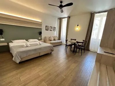 a bedroom with a bed and a living room with a table at Hôtel du Nord in Corte